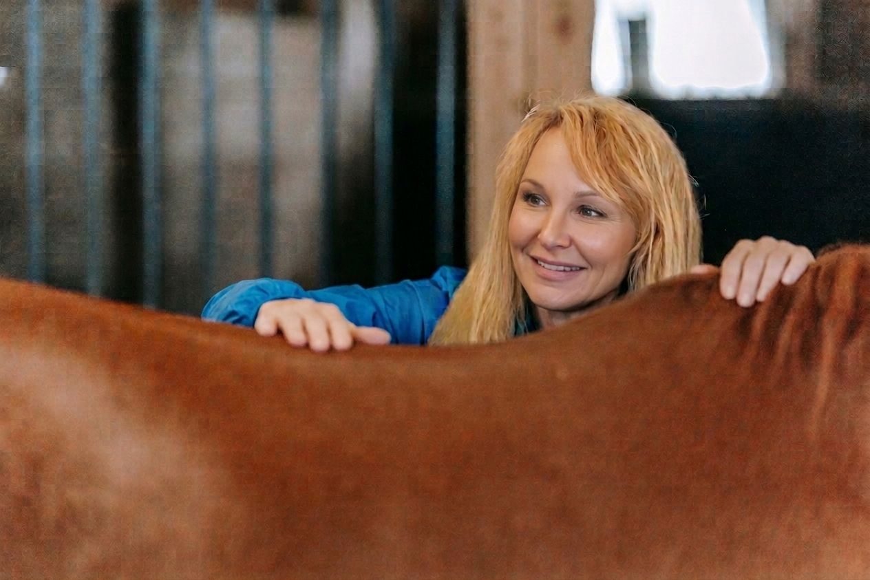 A woman massaging a horse in a warm stable